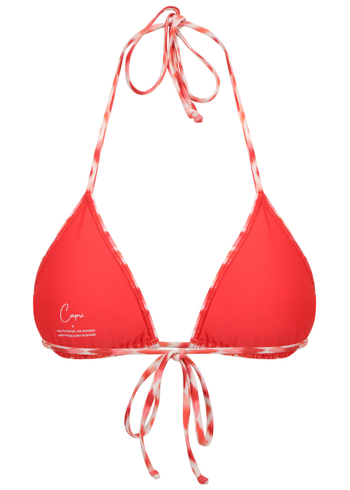 Juicy Top triangle style bikini top in red and white ikat-pattern inner view with red cloth cups, Capri Swim logo on left cup, adjustable neck and back ties, in white backdrop.