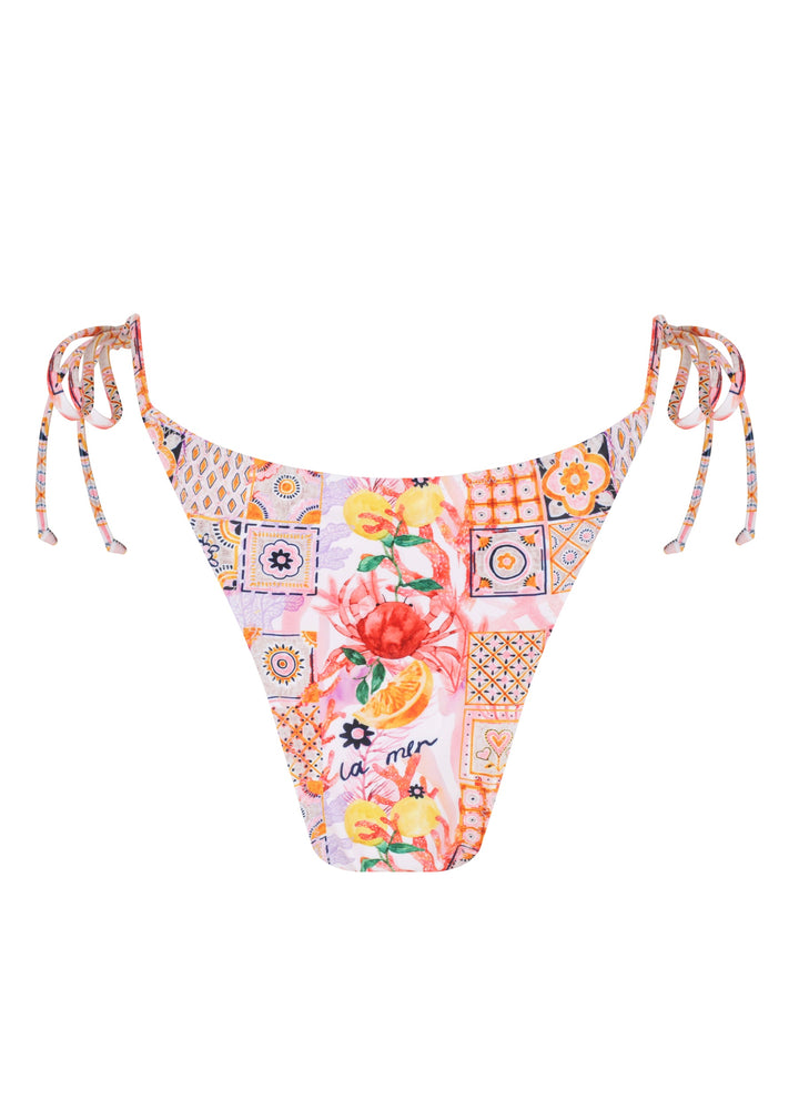 Back of colorful La Mer Classic Bottoms in classic triangle style with side ties with a vibrant patchwork of floral and geometric patterns, including fruits, flowers, tiles, and the word "la mer" on pink background, cheeky coverage, on a white backdrop. 
